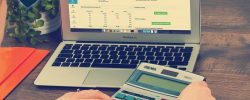 desk with a laptop and calculator in a woman’s hands
