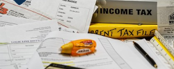 a closeup of calculator, highlighter, income tax textbooks and forms