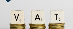 three stacks of coins with scrabble tiles stacked on them to spell out VAT