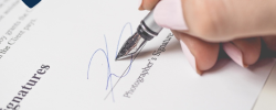 a close up of someone signing a contract with a nib pen