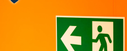 an emergency exit sign on an orange wall