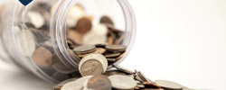 a mason jar tipped over with many coins pouring out of it