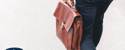 a person walking holding a brown leather bag