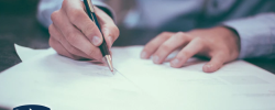 a close up photograph of a person signing a document