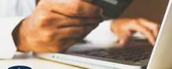 person using a laptop and holding a bank card
